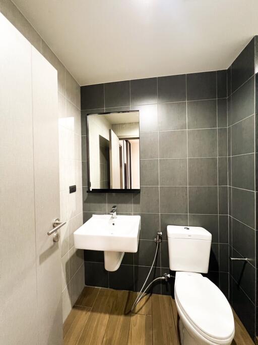 Modern bathroom with dark tiled walls and wooden floor
