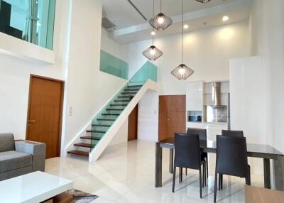 Modern living and dining area with high ceilings and staircase