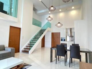 Modern living and dining area with high ceilings and staircase