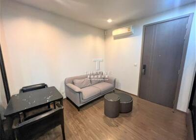 Cozy living room with wooden flooring, a gray sofa, small table, and an air conditioning unit.