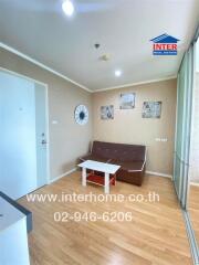 Cozy living room with a brown sofa, white coffee table, wooden floor, and wall decor