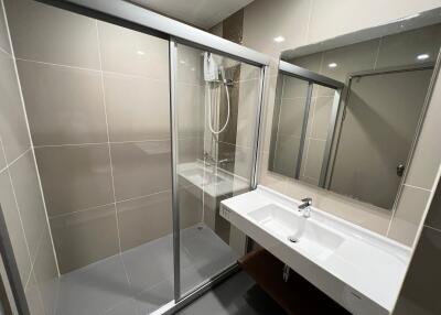 Modern bathroom with glass-enclosed shower, large mirror, and sleek white sink