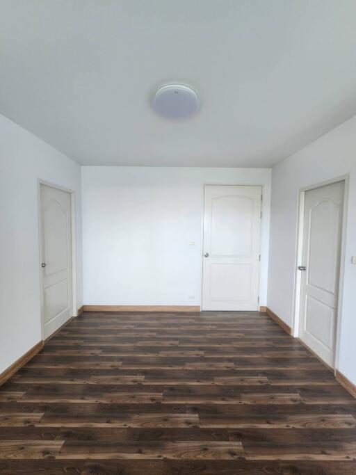Empty bedroom with wooden flooring and white doors