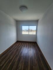 Empty bedroom with wooden floor and large window