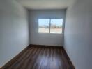 Empty bedroom with wooden floor and large window