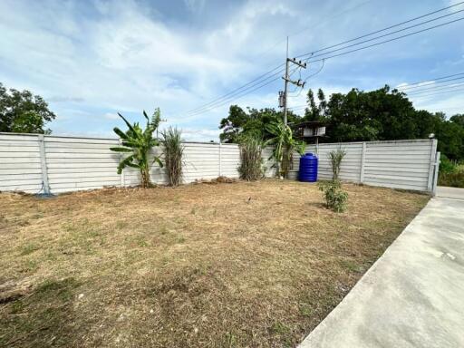 Fenced backyard with dry grass and some plants