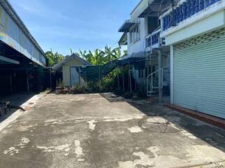 Sunny backyard with concrete patio and surrounding buildings