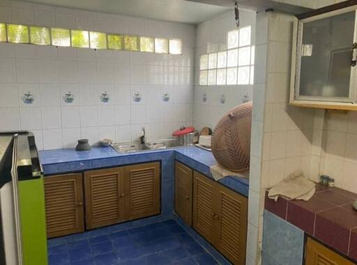 A traditional kitchen with wooden cabinets, tiled walls, and a double sink.