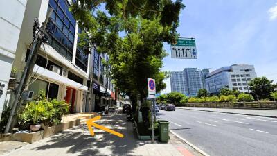 Street view of commercial buildings and sidewalk with trees on a sunny day