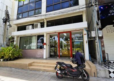 Entrance to a commercial building with glass windows and a motorbike parked outside