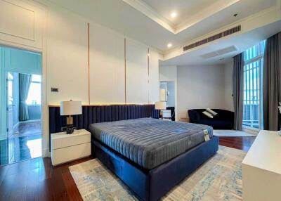 Well-lit modern bedroom with a large bed and comfortable seating area