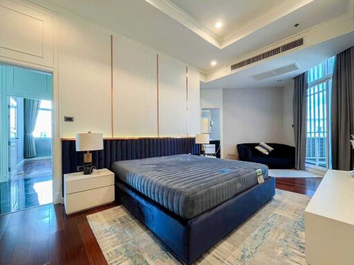 Well-lit modern bedroom with a large bed and comfortable seating area