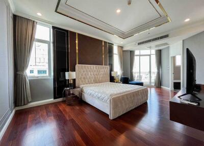 Spacious bedroom with large bed, wooden floor, modern decor, and natural light