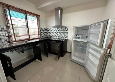 Modern kitchen with open refrigerator, checkered backsplash, and black cabinets