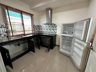 Modern kitchen with open refrigerator, checkered backsplash, and black cabinets