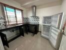 Modern kitchen with open refrigerator, checkered backsplash, and black cabinets