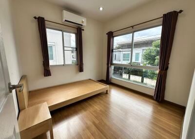 Simple unfurnished bedroom with wooden floor and large windows