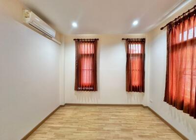 Bedroom with wooden floor, windows with dark curtains, and air conditioning unit