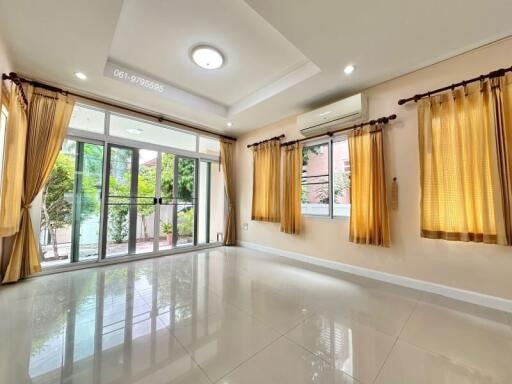 spacious living room with large windows and glass doors opening to a garden