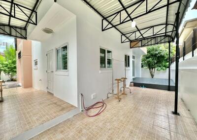 Covered outdoor space with tiled flooring and surrounding greenery