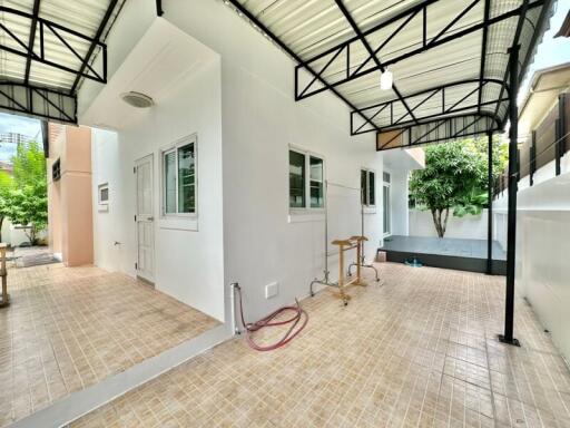 Covered outdoor space with tiled flooring and surrounding greenery