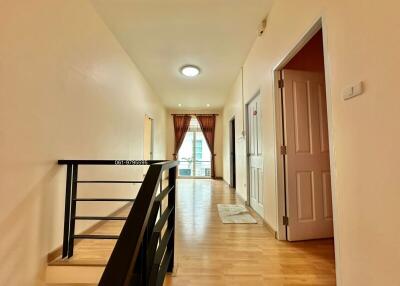 Hallway with doors, railing, and window with curtains