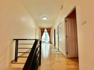 Hallway with doors, railing, and window with curtains