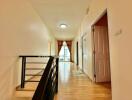 Hallway with doors, railing, and window with curtains