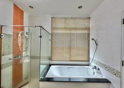 Spacious bathroom with bathtub and glass shower enclosure