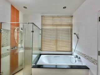 Spacious bathroom with bathtub and glass shower enclosure