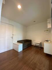 Simple living room with white walls, a dark couch and wooden floor