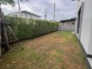 Side yard with grass and surrounding greenery