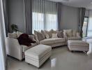 Modern living room with white sofas, large windows, and a plush teddy bear