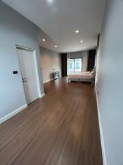 Spacious bedroom with wooden flooring and a large window