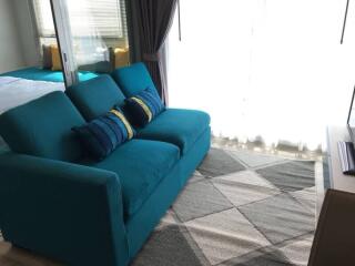 Living room with teal sofa and large windows