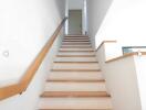 Indoor staircase with wooden handrail leading to a closed door