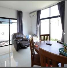 Living room with leather couch, dining table, and large windows