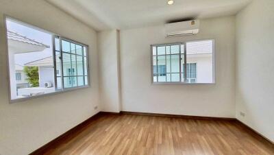 Empty bedroom with wooden flooring and two windows