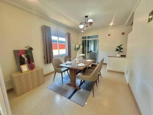 A well-lit dining area with a wooden table set for four, minimalist decor, and large window.