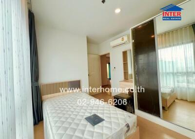 A bright bedroom with a bed, mirrored wardrobe, and wooden floor