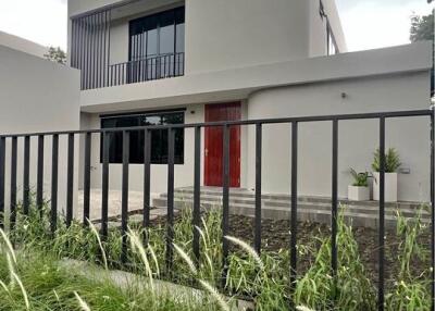 Front view of a modern two-story house with a garden and fence