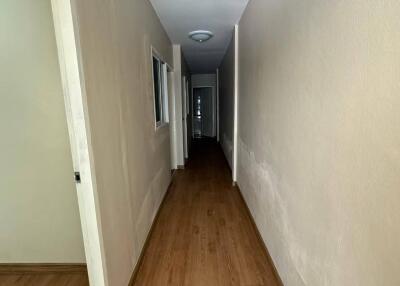 Narrow hallway with wooden floor and beige walls