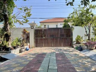 Gated driveway with large tiles and garden area