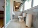 Modern bathroom with glass door, white fixtures, and large mirror