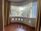 Curved bay window with tree views and hardwood flooring