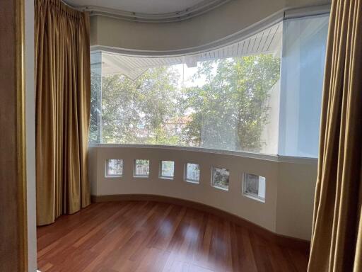 Curved bay window with tree views and hardwood flooring