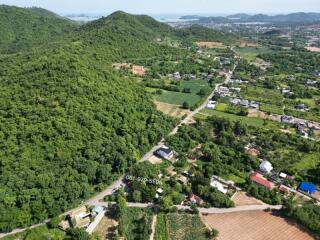 Aerial view of a lush green hilly area with scattered residential properties