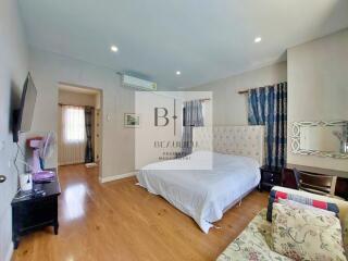 Spacious bedroom with double bed, wooden flooring, and natural light