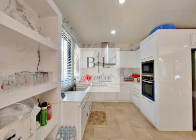 Modern kitchen with white cabinetry, marble backsplash, and built-in appliances