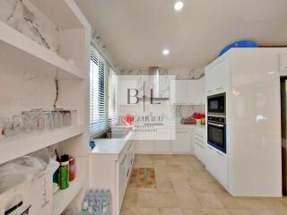 Modern kitchen with white cabinetry, marble backsplash, and built-in appliances